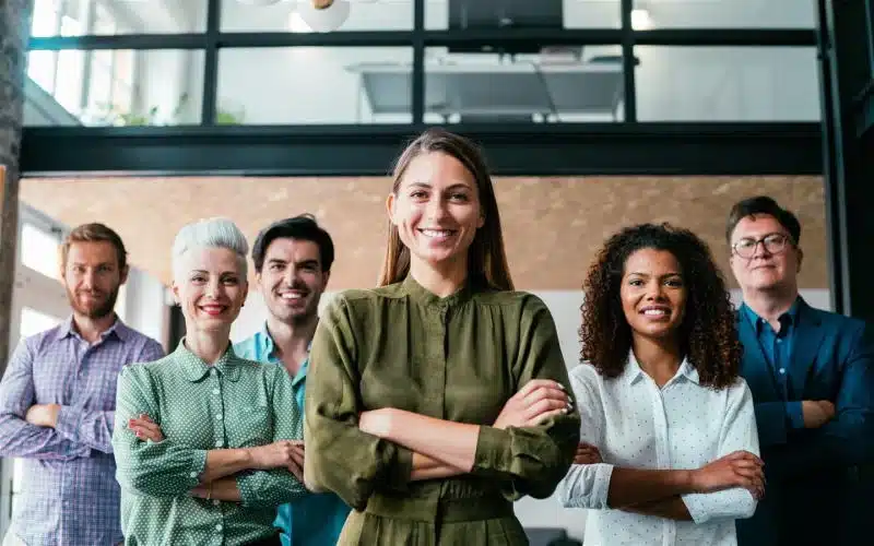 diverse group six workers in an office with arms crossed
