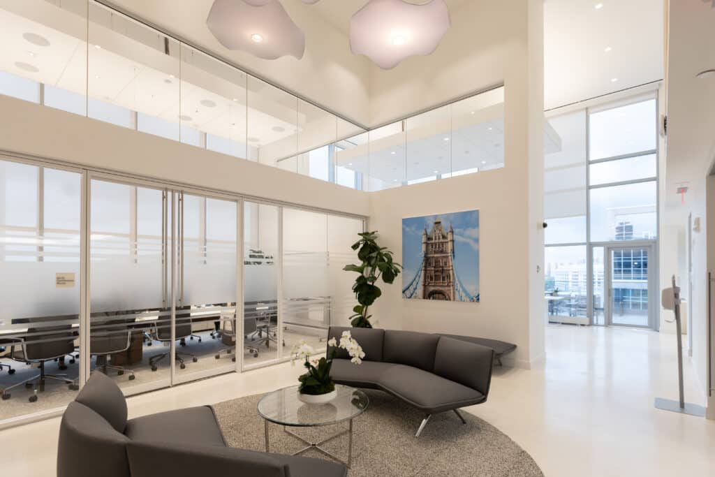 Modern LGRA office lobby with glass walls, gray lounge chairs, and large photo of Tower Bridge on display