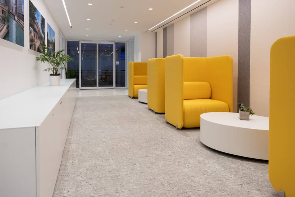 Modern office lounge at LGRA with bright yellow privacy chairs and minimalist white tables